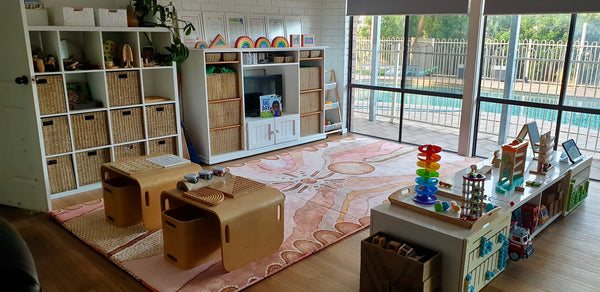 A bright playroom filled with various toys and a large window letting in natural light.