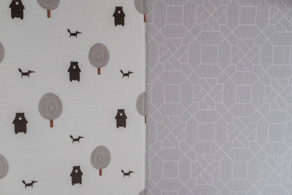 Two sides of Forrest Grey playmat. Side A has a grey geometric pattern and side B has a tree and bear pattern. 