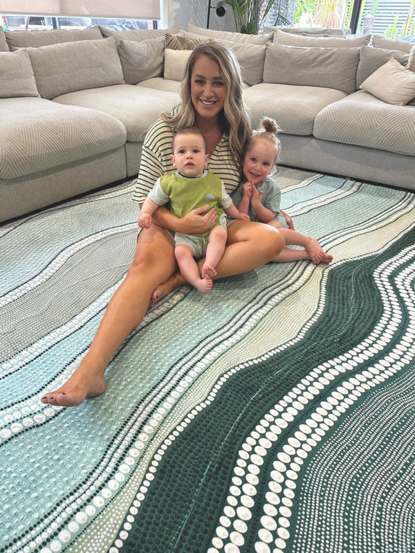 A woman and two children sitting together on a colorful rug, engaged in a playful activity.