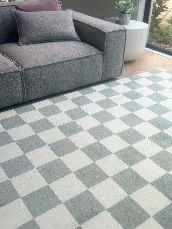 Gray and white checkerboard rug in a living room with a gray sofa.