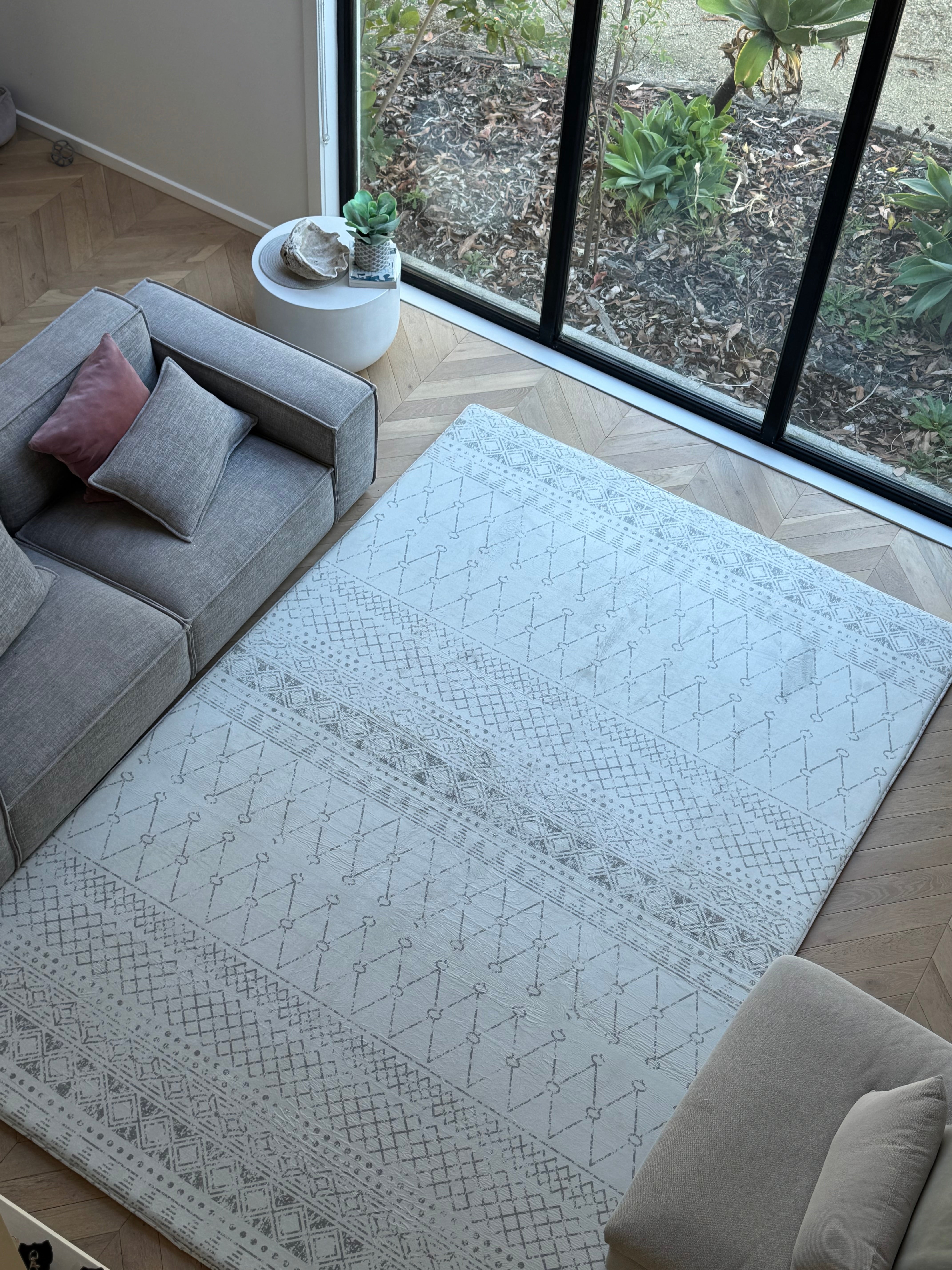 A spacious living room with a large area rug and a plush couch, designed for comfort and style.