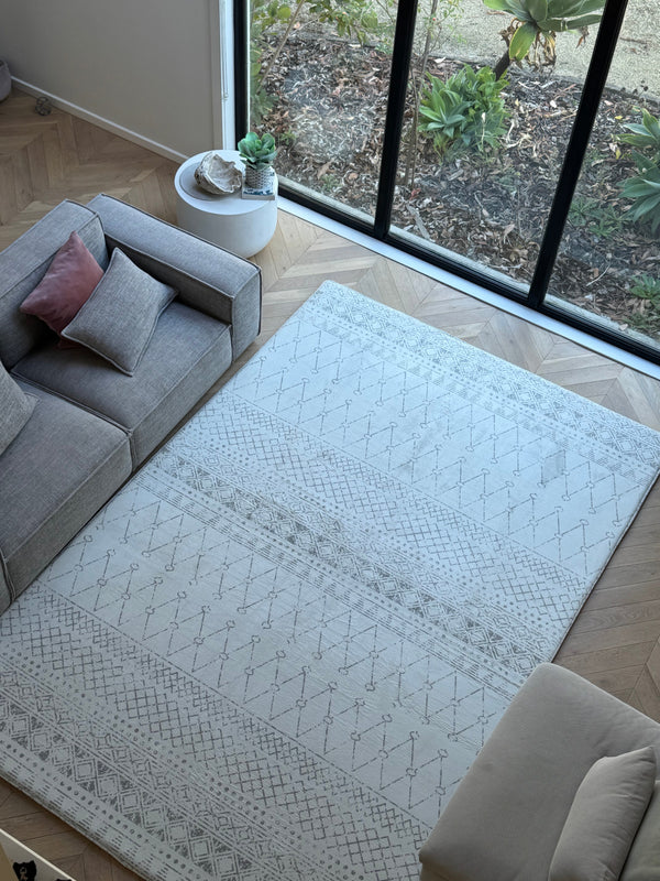 A spacious living room with a large area rug and a plush couch, designed for comfort and style.