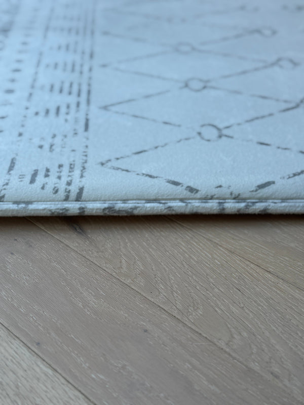 A white rug featuring a geometric pattern, showcasing a modern design suitable for various interior styles.