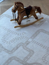 A plush rocking horse sits on a light-colored rug with a printed road and railroad track pattern.